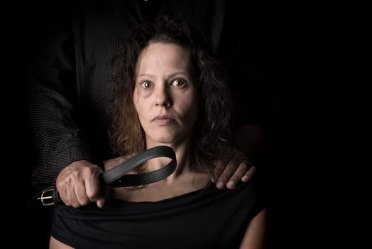 Abused woman victim of domestic violence, with husband hand holding a belt as a weapon.