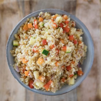 Bowl of vegan bulgur pilaf with carrots, red peppers, onions and zucchini.