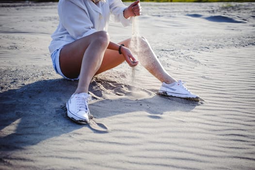 lovely young woman with curly hair, the romance of youth, a journey walk on a warm summer sunny day on a sandy beach with water