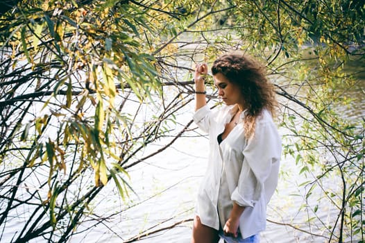 lovely young woman with curly hair, the romance of youth, a journey walk on a warm summer sunny day on a sandy beach with water