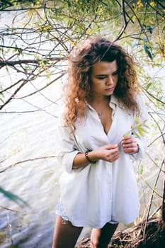 lovely young woman with curly hair, the romance of youth, a journey walk on a warm summer sunny day on a sandy beach with water