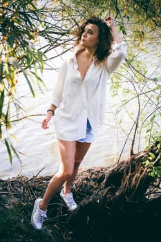 lovely young woman with curly hair, the romance of youth, a journey walk on a warm summer sunny day on a sandy beach with water