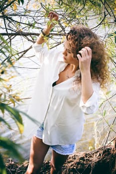 lovely young woman with curly hair, the romance of youth, a journey walk on a warm summer sunny day on a sandy beach with water