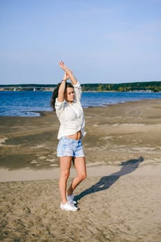 lovely young woman with curly hair, the romance of youth, a journey walk on a warm summer sunny day on a sandy beach with water