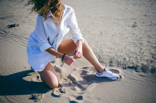 lovely young woman with curly hair, the romance of youth, a journey walk on a warm summer sunny day on a sandy beach with water