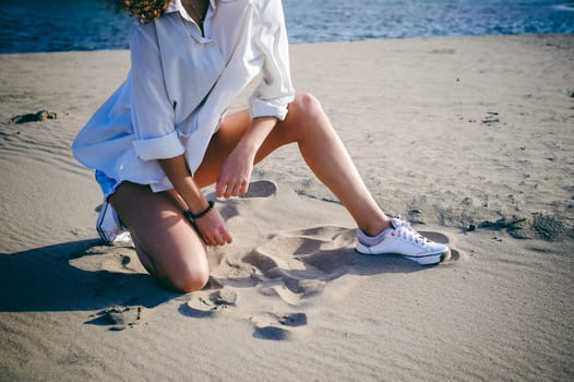 lovely young woman with curly hair, the romance of youth, a journey walk on a warm summer sunny day on a sandy beach with water