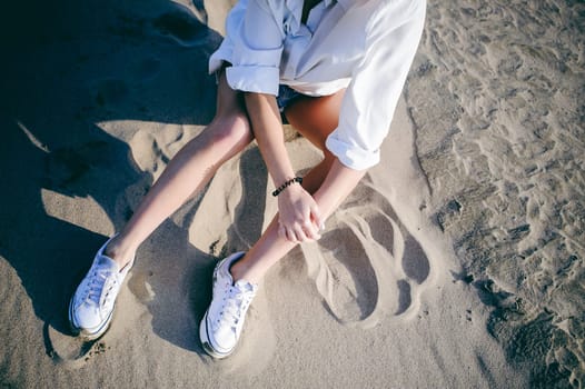 lovely young woman with curly hair, the romance of youth, a journey walk on a warm summer sunny day on a sandy beach with water