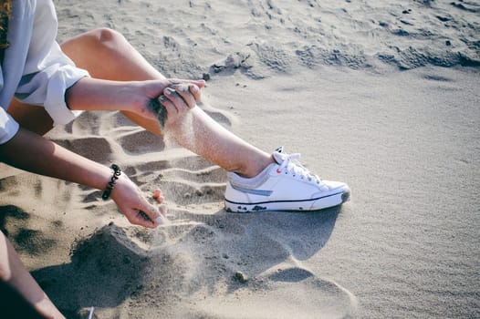 lovely young woman with curly hair, the romance of youth, a journey walk on a warm summer sunny day on a sandy beach with water