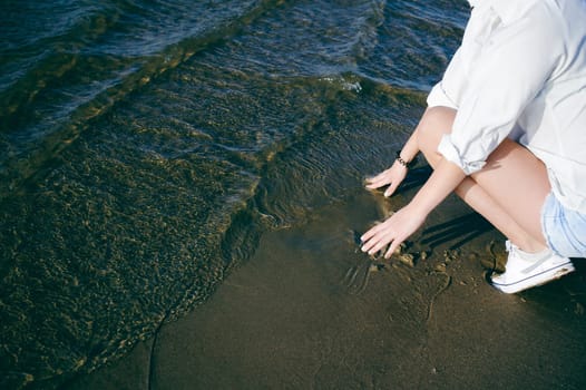lovely young woman with curly hair, the romance of youth, a journey walk on a warm summer sunny day on a sandy beach with water