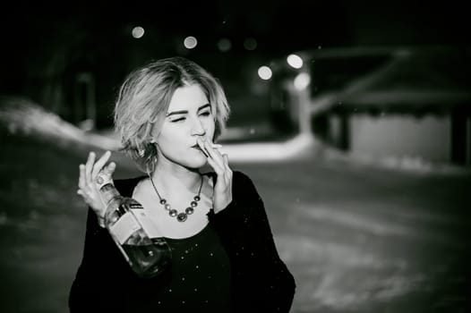 Black and white portrait of a girl with a cigarette. young beautiful woman with dyed hair smoking a cigarette in the street under the snow