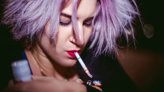 Portrait of a girl with a cigarette. young beautiful girl hipster smoking a cigarette in the street under the snow. her hands lights a lighter, lighting a cigarette tobacco