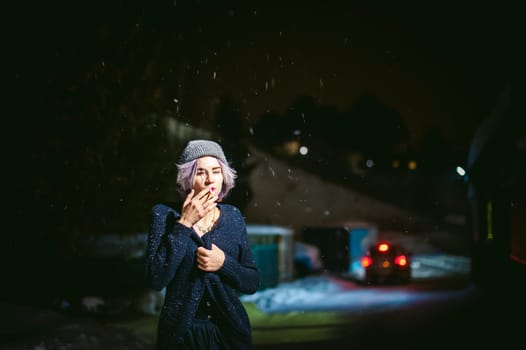 Portrait of a girl with a cigarette. young beautiful girl with dyed hair hipster hat. cigarette smoking on the street under the snow