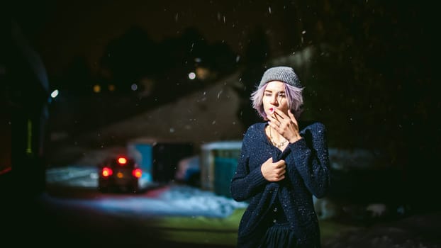 Portrait of a girl with a cigarette. young beautiful girl with dyed hair hipster hat. cigarette smoking on the street under the snow