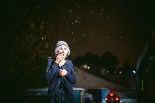 Portrait of a girl with a cigarette. young beautiful girl with dyed hair hipster hat. cigarette smoking on the street under the snow