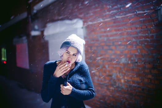 Portrait of a girl with a cigarette. young beautiful girl with dyed hair hipster hat. cigarette smoking on the street under the snow