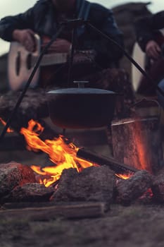 Closeup photo of the man playing o guitar near the campfire
