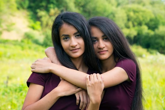 Adult female twins hugging each other - exterior shot