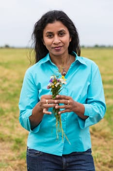 Attractive woman with self-picked flowers on summer meadow