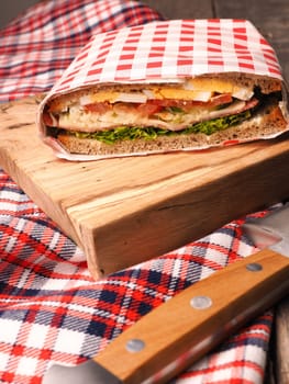 Tasty homemade sandwich with organic ingredients like eggs, tomatoes, salami, cheese and fresh lettuce