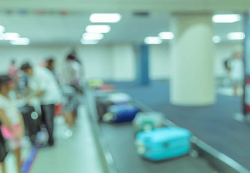 Blurred image background of passengers wait for luggage at baggage claim in airport. Blue tone color image
