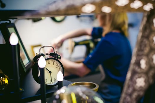 round the clock on a blurred background. seamstress work on the sewing machine. young blond woman working on a mechanical sewing machine at home sitting at your desk, be prepared to sew
