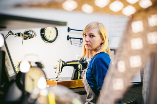 seamstress work on the sewing machine. young blonde woman working on a mechanical sewing machine at home sitting at your desk, be prepared to sew