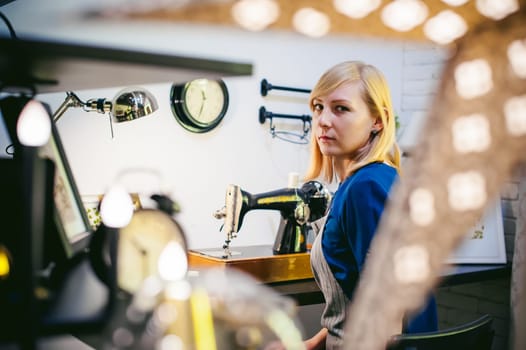 seamstress work on the sewing machine. young blonde woman working on a mechanical sewing machine at home sitting at your desk, be prepared to sew
