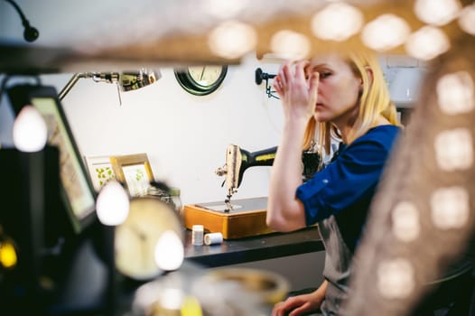 seamstress work on the sewing machine. young blonde woman working on a mechanical sewing machine at home sitting at your desk, be prepared to sew