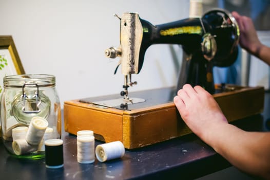 Hands seamstress work on the sewing machine. young blond woman working on a mechanical sewing machine at home sitting at your desk, be prepared to sew