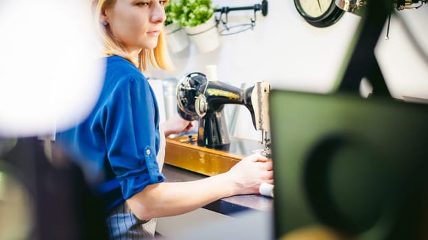 seamstress work on the sewing machine. young blonde woman working on a mechanical sewing machine at home sitting at your desk, be prepared to sew