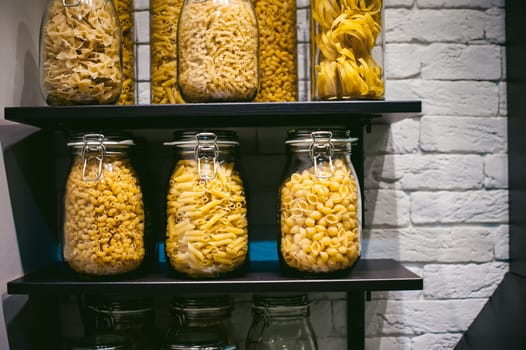 pasta in the jar. on kitchen shelves are different kinds of pasta in glass jars