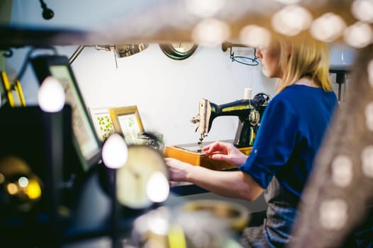 seamstress work on the sewing machine. young blonde woman working on a mechanical sewing machine at home sitting at your desk, be prepared to sew