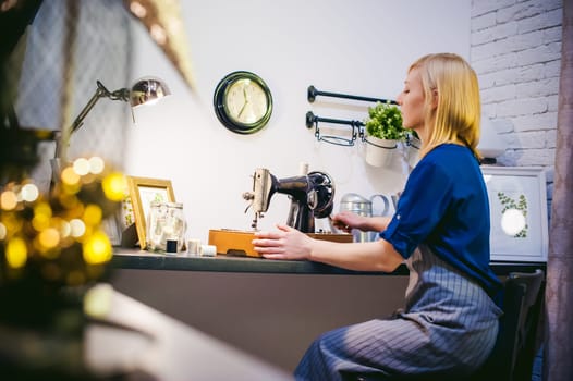 seamstress work on the sewing machine. young blonde woman working on a mechanical sewing machine at home sitting at your desk, be prepared to sew