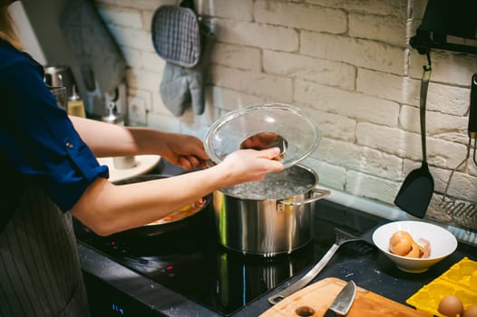 woman housewife preparing pasta in the kitchen. woman's hand dipped spaghetti in boiling water for cooking
