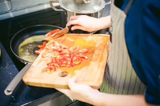 woman housewife prepares fried eggs with ham and vegetables in his kitchen. cut peppers and tomatoes, and puts them in a frying pan