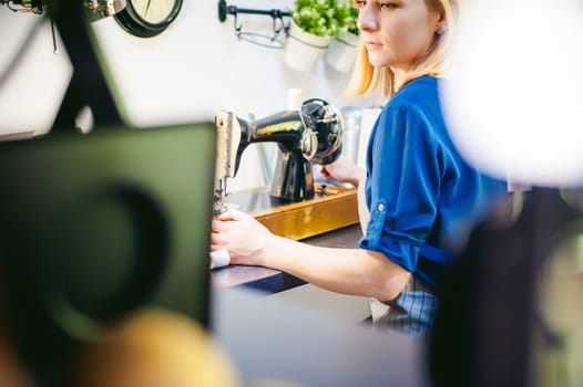 seamstress work on the sewing machine. young blonde woman working on a mechanical sewing machine at home sitting at your desk, be prepared to sew