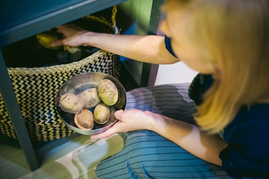 woman housewife in the kitchen. girl picking out of the bag potatoes for cooking