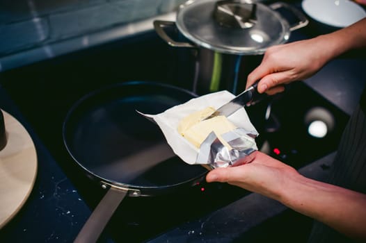 woman housewife prepares fried eggs with ham and vegetables in his kitchen. spreads the butter in the pan