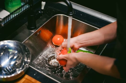 woman washing vegetables for cooking, water under the tap