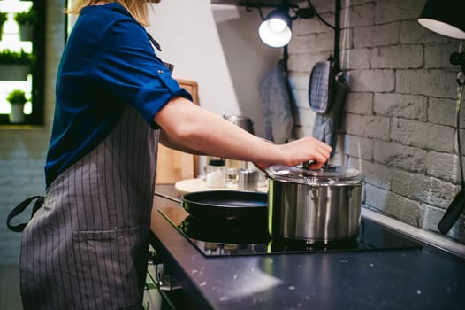 woman housewife in the kitchen. girl collects water from the tap in the pan