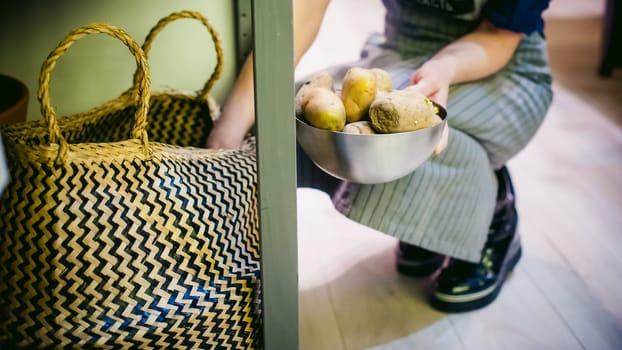 woman housewife in the kitchen. girl picking out of the bag potatoes for cooking