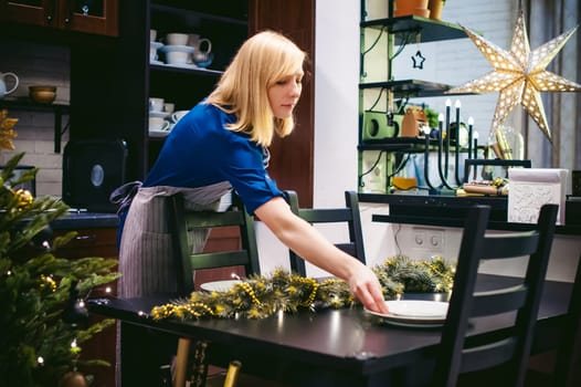 woman housewife setting the table. young blonde in a dress and apron, served in a dining table, puts the dishes, doing the work in the kitchen