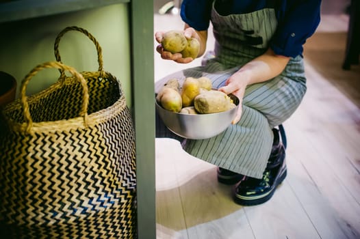 woman housewife in the kitchen. girl picking out of the bag potatoes for cooking