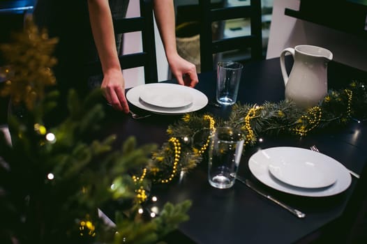 woman housewife setting the table. young blonde in a dress and apron, served in a dining table, puts the dishes, doing the work in the kitchen. lays out the forks and knives to persons