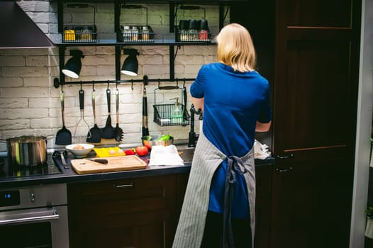 woman housewife setting the table. young blonde in a dress and apron, served in a dining table, puts the dishes, doing the work in the kitchen.