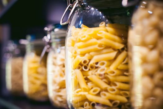 pasta in the jar. on kitchen shelves are different kinds of pasta in glass jars