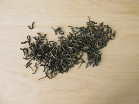 Green tea Chun Mee from China on a wooden board