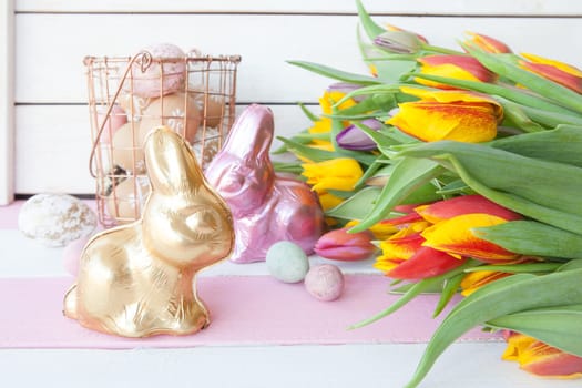 Lots of colorful Easter bunnies made of chocolate and fresh tulips