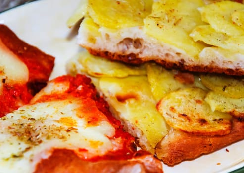 close up of two slices of pizza with tomato, mozzarella and potatoes
