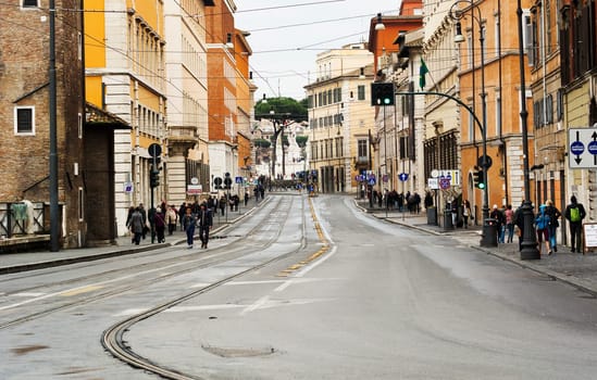 Rome, Italy, march 2015: view of Via delle Botteghe Oscure in Rome with the tram rails and people walking on a rainy day